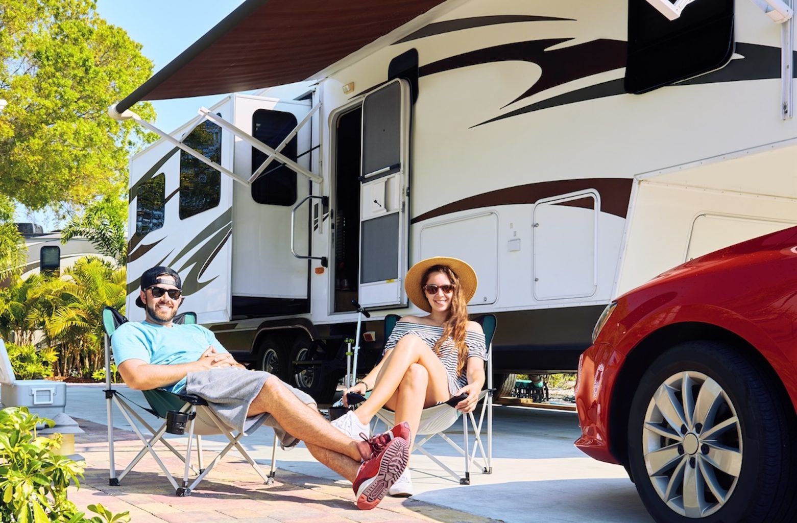 Happy couple sitting oon camping chairs outside the right RV for their lifestyle
